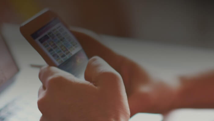 Imagem mostra duas mãos a segurar um telemóvel com Nossa Aposta App instalada