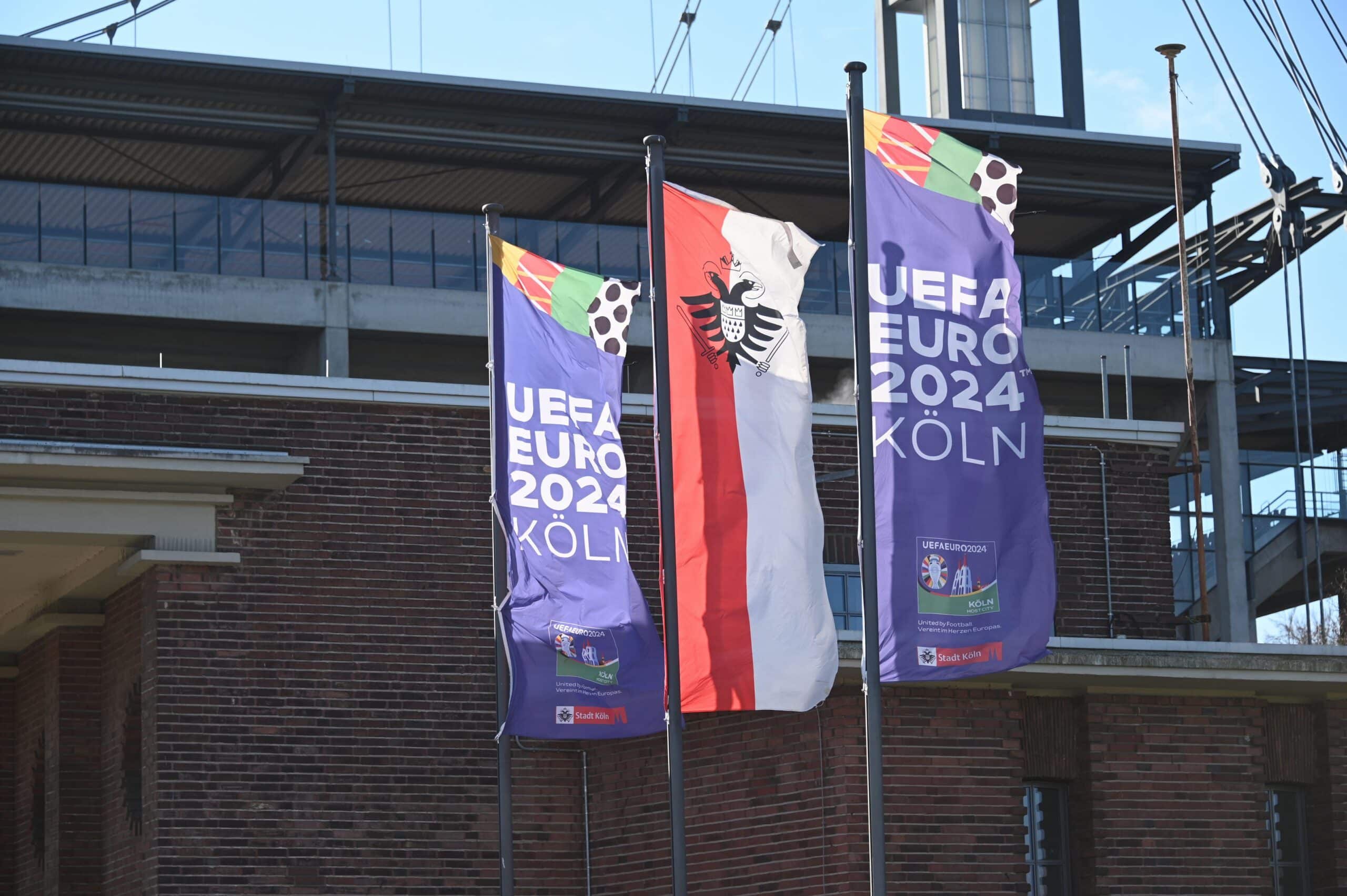 2NWYEX9 Cologne, Germany. 28th Feb, 2023. The flag of the European Football Championship 2024 - officially UEFA EURO 2024 Cologne - and the flag of the city of Cologne with coat of arms flies in front of the Rheinenergie Stadium Credit: Horst Galuschka/dpa/Alamy Live News